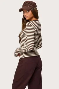 Side view of woman wearing a brown striped slim fit long sleeve shirt and crochet hat