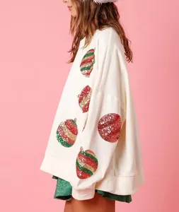 Détail de côté d'un sweat-shirt blanc avec motifs de boules de Noël en paillettes