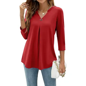 Detail of red V-neck 3/4 sleeve top with pleated front and decorative metal button.