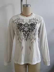 Primer plano del estampado gráfico de alas vintage y rosas en top blanco de manga larga.