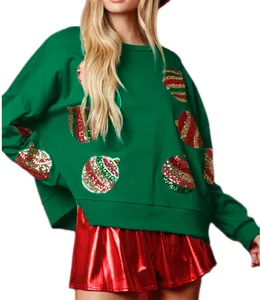 Détail d'un sweat de Noël vert pour femme avec des motifs de boules en paillettes