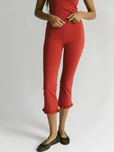 Detailed view of women's solid red cropped capri pants featuring a stylish ruffled hemline