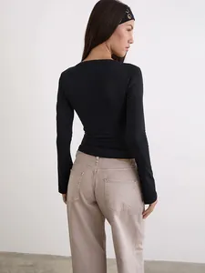 Vista trasera detallada de un top negro de manga larga ajustado con pantalones beige