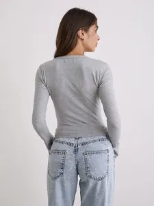 Vista posterior de un top gris de manga larga ajustado combinado con vaqueros claros