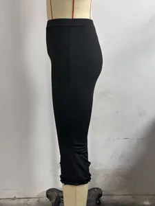 Side view detail of black cropped pants with ruffled hems on a mannequin display