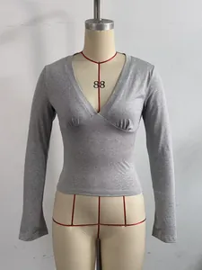 Vista detallada de un top gris de manga larga con escote en V profundo en un maniquí.
