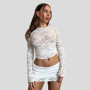 Close-up detail of exquisite white floral lace pattern on sheer long-sleeved mesh top