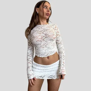 Detailed view of white floral lace long sleeve sheer crop top and matching mini skirt.