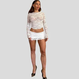 Full view of a model wearing a white sheer lace long-sleeve top and mini skirt outfit