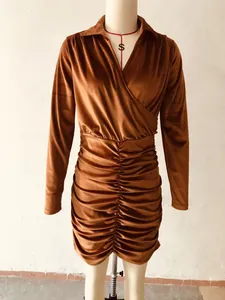 Detailweergave van karamelkleurige fluwelen jurk met V-hals en geplooide taille