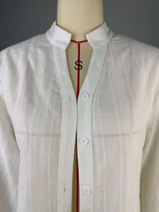 Detalle de una camisa blanca con cuello mao, elegante tejido texturizado y mangas abullonadas
