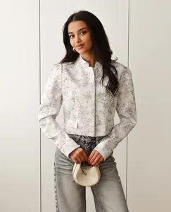 Close-up view of elegant white short blazer with purple ink floral print on model
