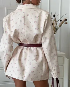 Close-up back view of a cream floral blazer with pink flowers and a burgundy belt.