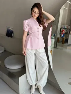 Dettaglio dell'elegante blazer rosa a maniche corte abbottonato con vita strutturata.