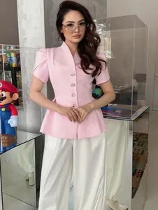 Vista dettagliata di un elegante blazer rosa a maniche corte con orlo peplo e maniche a sbuffo