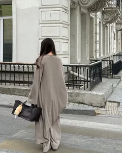Vista posteriore di una donna in completo 3 pezzi cardigan lungo e pantaloni beige