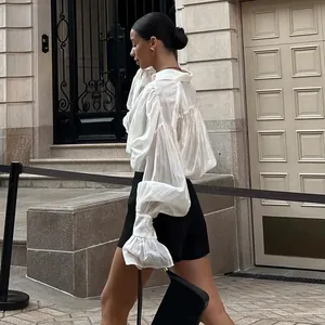 Vue détaillée d'une blouse blanche ample avec manches lanternes élégantes et poignets plissés.