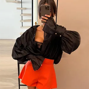 Chemise noire ample à manches lanterne avec un short orange vif à taille haute