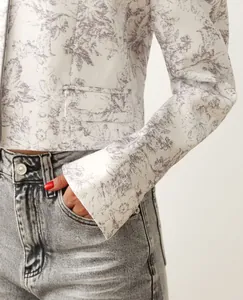 Close-up detail of white cropped blazer with elegant gray ink wash floral print.