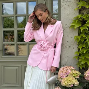 Elegant detail showing pink blazer with large 3D rose decoration and tie-waist design