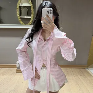 Selfie en el espejo de una mujer con una camisa rosa a rayas ajustada de manga larga