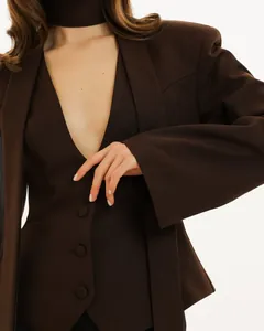 Gros plan d'un blazer marron à col en V avec écharpe intégrée et boutons élégants