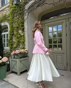 Elegant pink blazer with tie-waist and white pleated skirt set in outdoor garden