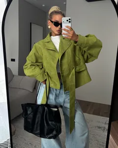 Chaqueta corta verde de moda con cuello alto y cinturón en un atuendo con estilo