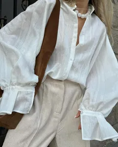 Close-up view of a stylish white loose-fit long-sleeve shirt with subtle striped texture