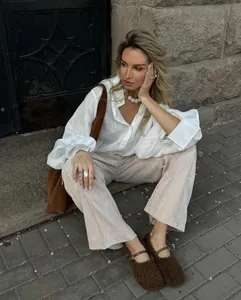 Detailed view of a white loose-fit long-sleeve shirt featuring textured fabric and lapel