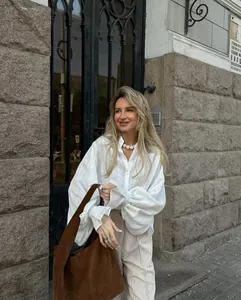 Elegant white oversized puff sleeve shirt styled with a brown suede tote bag.