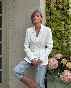 Elegant white loose blazer featuring a stylish large fabric flower and waist tie closure