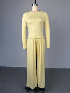 Dettaglio di set due pezzi giallo con top a maniche lunghe e pantaloni a vita alta.