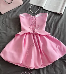 Close-up of pink strapless top and bubble skirt set with lace-up back detail on gray background.