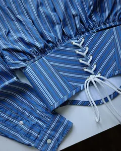 Detailed macro view of a blue and white striped long sleeve shirt with lace-up waist detail