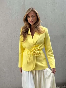 Detailed view of bright yellow blazer with 3D flower waist decoration and belted tie