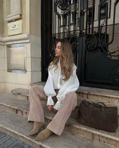 Detail view of a stylish white long-sleeve shirt with puff sleeves and corduroy pants