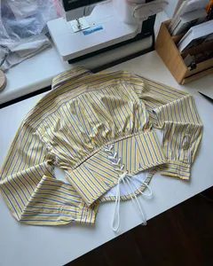 Detail of the yellow and blue striped cropped shirt featuring a back lace-up waist design