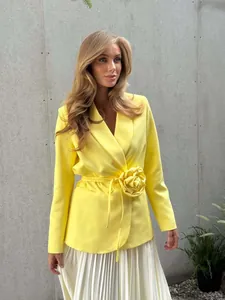 Detailed view of yellow blazer with 3D flower accent and waist-cinching tie belt