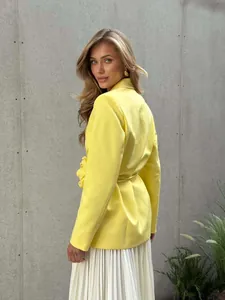 Side view detail of yellow blazer featuring a decorative 3D flower and waist tie.