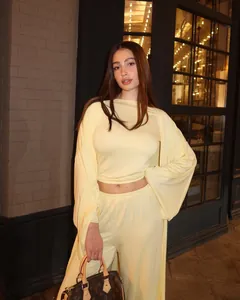 Modella indossa un set lounge tre pezzi giallo pallido con cardigan lungo e pantaloni