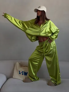 Detailed macro view of a shiny green satin tracksuit with a loose fit and wide-leg design.