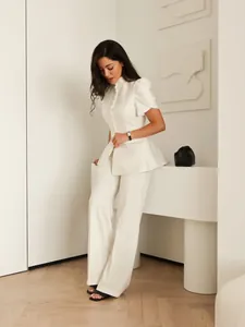 Dettaglio elegante blazer bianco a peplo con maniche a sbuffo e bottoni frontali