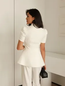 Dettaglio del blazer bianco con maniche a sbuffo e baschina, vestibilità sciancrata