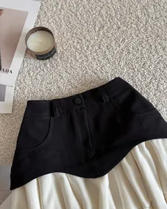 Primer plano detallado de una minifalda plisada de línea A en negro y crema suave