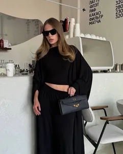 Set casual nero in tre pezzi con cardigan lungo e pantaloni a vita alta in un caffè