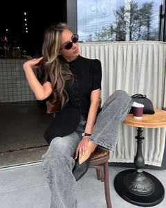 Dettaglio di un elegante top nero a maniche corte con bottoni in un caffè