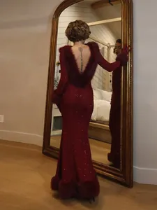 Back detail of a sparkling burgundy backless mermaid gown with plush faux fur trim