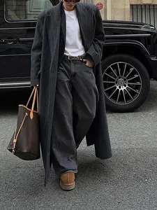 Langer anthrazitfarbener Nadelstreifenmantel, gestylt mit lockeren Jeans und Tragetasche.