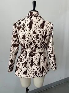 Vue arrière détaillée d'un blazer à manches longues imprimé vache marron et blanc avec ceinture.